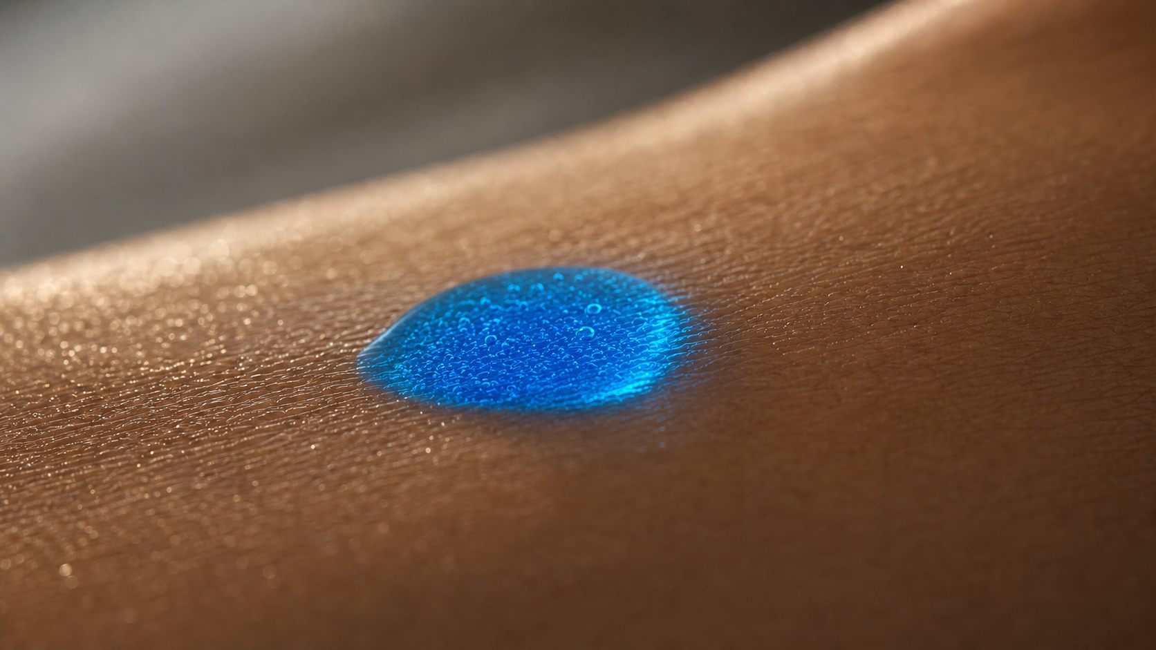 Macro close-up of Copper Peptide Elixir: water-light blue serum droplet with fine bubbles on luminous skin